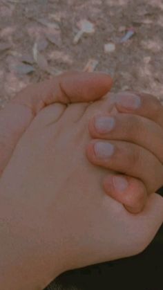 two hands holding each other in the dirt