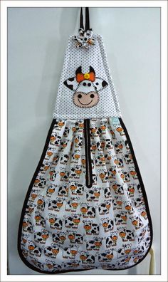 a white and black cow print bag hanging on a wall with an orange bow around it's neck