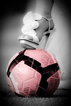 a woman's foot on top of a pink soccer ball