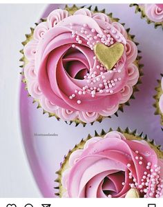 three cupcakes with pink frosting and sprinkles are on a plate