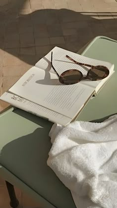 an open book with sunglasses sitting on top of it