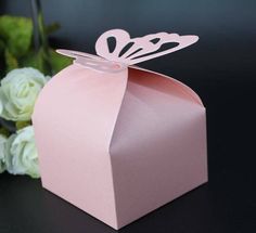 a pink gift box with a butterfly on the top and white flowers in the background