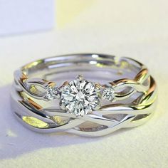 an engagement ring with two bands and a round diamond in the center, sitting on a white surface