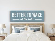 a bedroom with a bed, nightstands and a sign that says better to wake at the lake