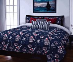 a bed covered in blue and red comforter next to a painting on the wall