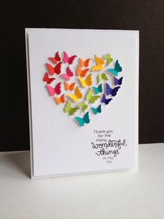 a card with colorful butterflies in the shape of a heart, on top of a table