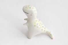 a small white toy dinosaur sitting on top of a table