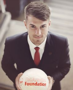 a man in a suit and tie holding a soccer ball with the words foundation on it