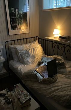 a laptop computer sitting on top of a bed next to a night stand and lamp