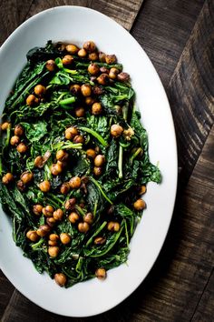 spinach and chickpeas in a white bowl on top of a wooden table