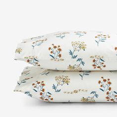 two pillow cases with flowers on them, one is white and the other is orange