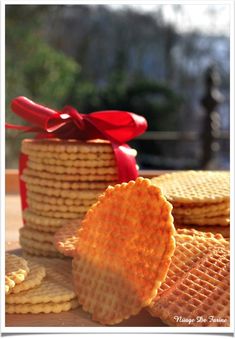 a stack of waffles with a red ribbon tied around it and some cookies in the background