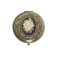 an antique looking compact mirror with a white rose on it