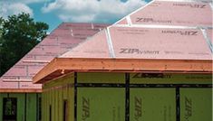 the roof is covered in pink insulation and some green doors are on the side of the building