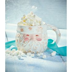 a mug with marshmallows in it and a santa face on the side