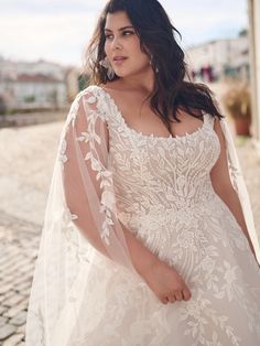 a woman in a wedding dress is standing on the cobblestone street with her arms behind her back