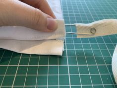 someone is cutting fabric with scissors on a green tablecloth that's being sewn together