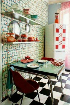 a kitchen with colorful wallpaper and black and white checkered flooring, red chairs