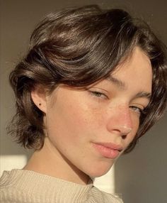 a close up of a person with freckles on her face and hair pulled back