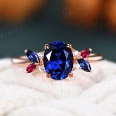 a blue ring with three different colored stones on it's side, sitting on top of a white blanket