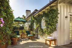 an outdoor patio with chairs and umbrellas next to a building covered in ivy leaves