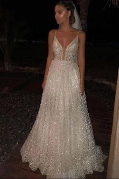 a woman in a wedding dress standing on a wooden deck at night with her back to the camera