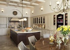 a large kitchen with an island and dining room table in the center, surrounded by white cabinets