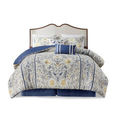 a bed with blue and white comforter set on top of it, next to pillows