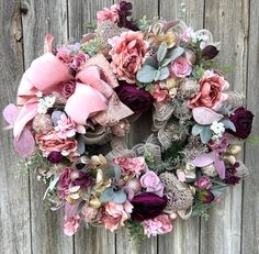 a wreath with pink and purple flowers hanging on a wooden fence