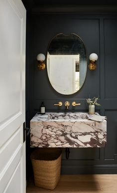 a bathroom with a marble sink and gold faucet, along with a round mirror on the wall