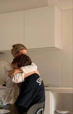 two people hugging each other in the kitchen