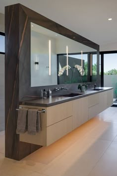 a large bathroom with two sinks and mirrors on the wall, along with an open window