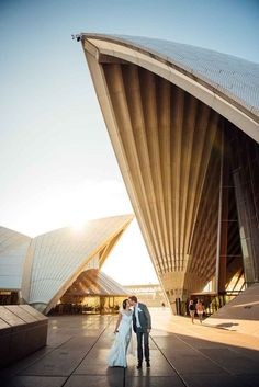 a bride and groom standing in front of the sydney opera house