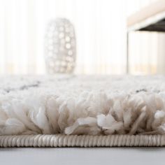 a close up of a rug on the floor with a table in the back ground