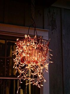 a chandelier hanging from the side of a building with lights strung through it