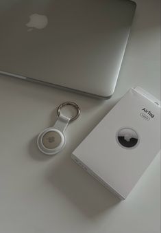 an apple laptop and keychain sitting next to each other on a white table