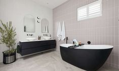 a bathroom with two sinks and a bathtub in the center, along with mirrors on the wall