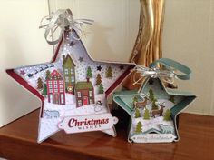 two star shaped christmas ornaments sitting on top of a wooden table