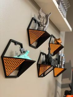 three black and orange triangle shaped shelves hanging on the wall with scissors, hairbrushes and other items