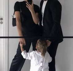 a man and woman standing next to each other in front of a mirror with their cell phones