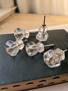 four glass knobs on top of a book with nails sticking out of them, sitting on a table