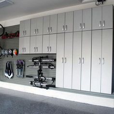 an organized garage with lots of cabinets and bicycles hanging on the wall in front of it