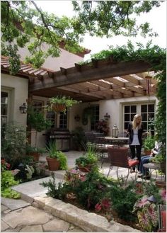 a woman standing in the middle of a patio with potted plants on either side