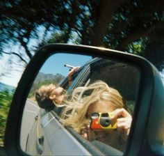 a woman taking a selfie in the side mirror of a car