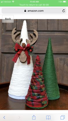 two small christmas trees sitting next to each other on top of a wooden table in front of a door