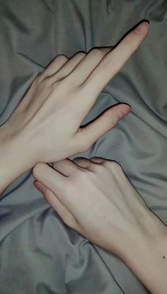 two hands touching each other on a bed