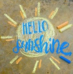 the words hello sunshine written in chalk and crayons next to pencils on concrete