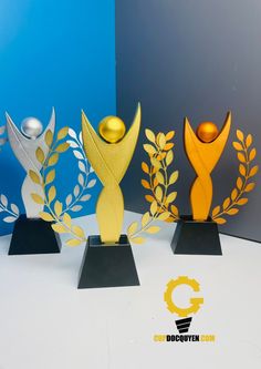 three award trophies sitting on top of each other in front of a blue and gray background