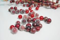 some red and white beads are laying on the table next to christmas tree branches,