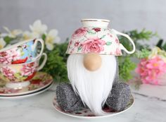 a gnome figurine sitting on top of a saucer with flowers around it